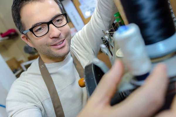 Spectacled man threading up sewing machine