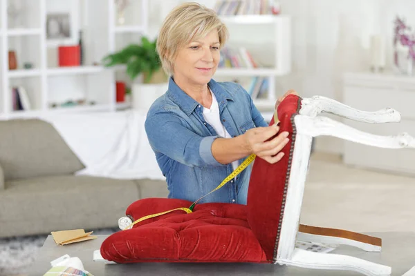 senior woman upholstering chair at home