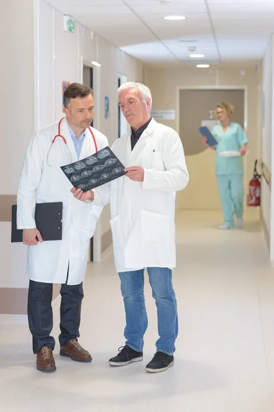 Δύο Άνδρες Ιατροί Συζητούν Αποτελέσματα Ακτινών Στο Διάδρομο Του Νοσοκομείου — Φωτογραφία Αρχείου