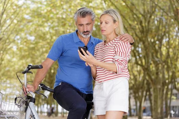 Γυναίκα Που Δείχνει Τηλέφωνο Στο Σύζυγο Κατά Διάρκεια Του Ποδηλάτου — Φωτογραφία Αρχείου