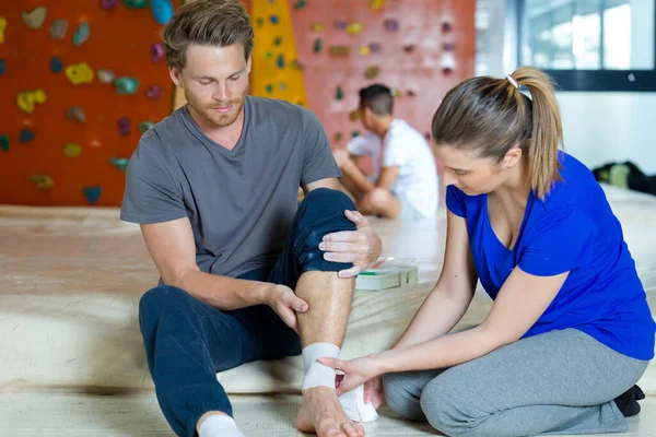 Vrouwelijke Trainer Wikkelen Verband Aan Gewonde Enkel — Stockfoto