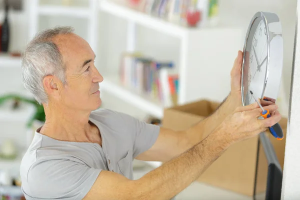 Senior Man Med Skruvmejsel Håller Klockan För Att Montera Väggen — Stockfoto