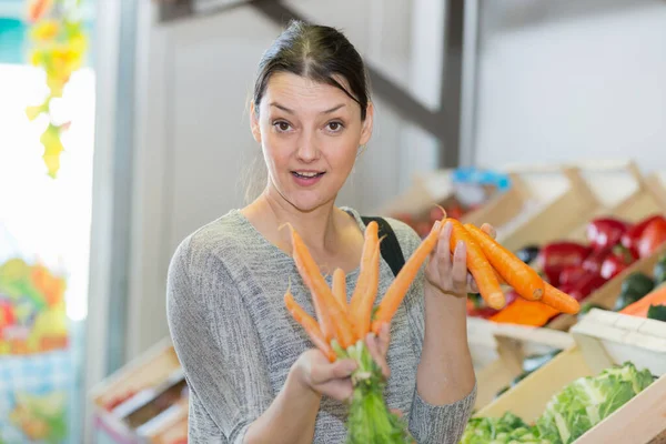 Frau Hält Karotten Neben Dem Verkaufsstand — Stockfoto