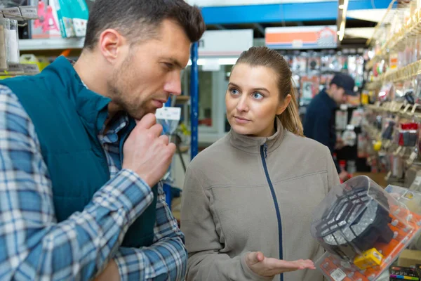 customer contemplating product sales assistant is proposing in hardware store