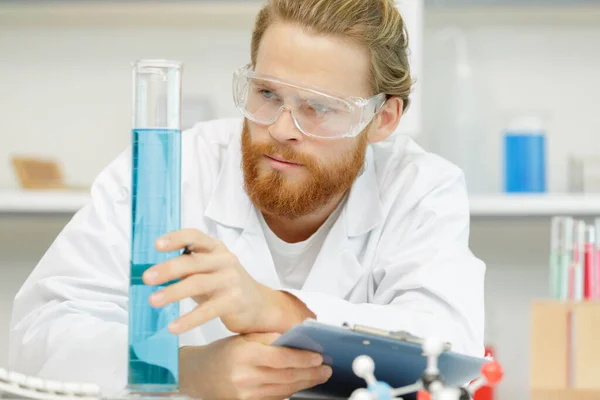 化学家用长笛把液体倒入玻璃瓶中 — 图库照片