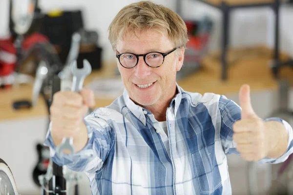 Man Shows Thumb While Repairing Bicycle Home — Stock Photo, Image