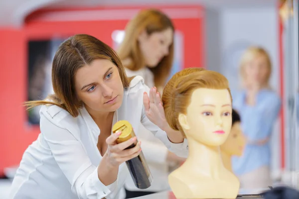 美容院学徒在人体模特假发上喷洒化学制剂 — 图库照片