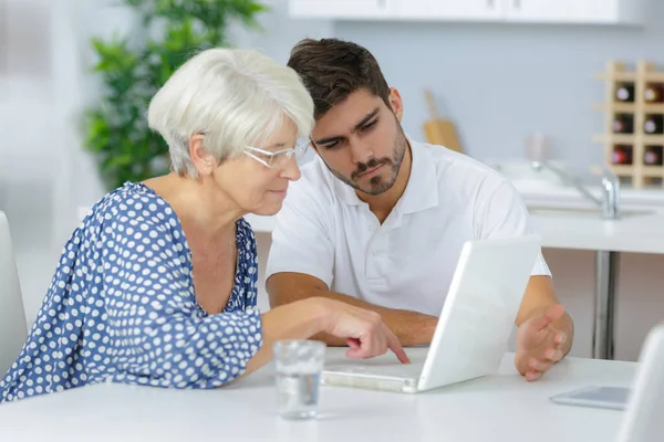 Jongeman Helpt Senior Dame Een Laptop Gebruiken — Stockfoto