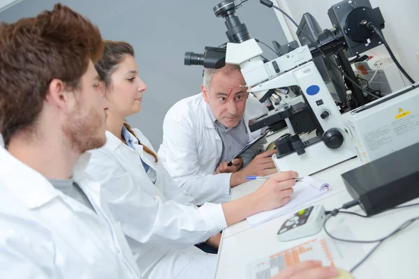 研究室に顕微鏡を持つ学生のグループ — ストック写真