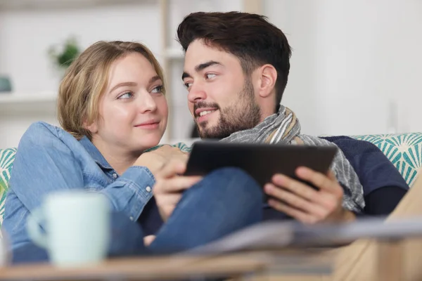 幸せなカップルとデジタルタブレット家庭でソファにしがみつく — ストック写真