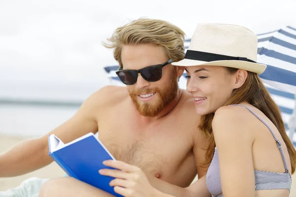 情侣们很高兴在海滩上看书 — 图库照片