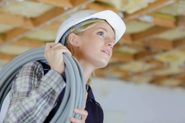 女建筑工人肩上背着电缆 — 图库照片