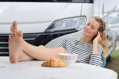 couple of tourists sit near their camper van having breakfast clipart