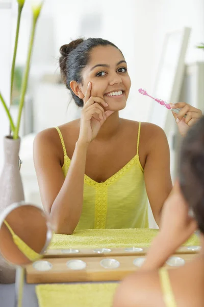 年轻的女人拿着牙刷坐在镜子前 — 图库照片