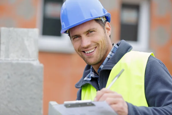 Schöner Glücklicher Arbeiter Der Auf Klemmbrett Schreibt — Stockfoto