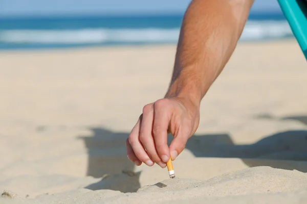 男の手がビーチの砂にタバコを突っ込み — ストック写真