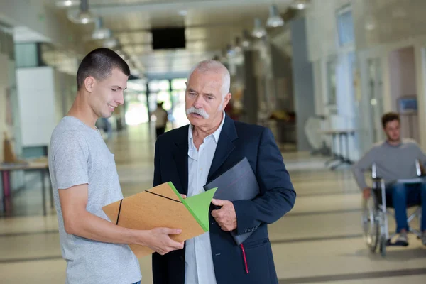 Nauczyciel Student Patrząc Przez Folder Korytarzu — Zdjęcie stockowe