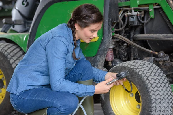 トラクターのタイヤをチェックする女性 — ストック写真
