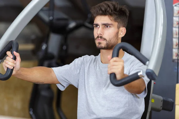 Férfi Edzés Bicepsz Gépen Egy Edzőteremben — Stock Fotó