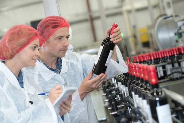 两个产业工人正在工厂里寻找瓶子 — 图库照片