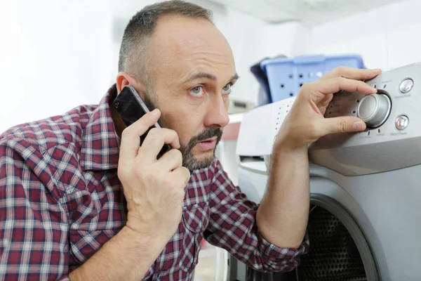 Uomo Che Parla Telefono Mentre Mette Bucato Lavatrice — Foto Stock
