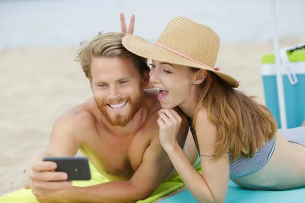 一对快乐的夫妇在海滩上用智能手机拍照 — 图库照片