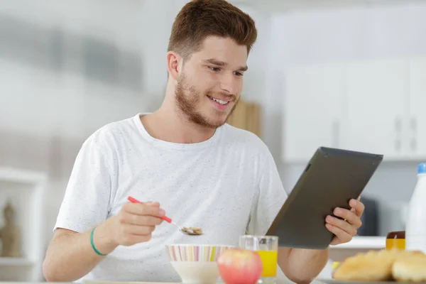 Dospívající Muž Dívá Tablet Zatímco Snídá — Stock fotografie