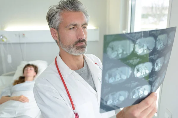 Arzt Untersucht Scan Ergebnisse Patient Krankenhausbett Hintergrund — Stockfoto