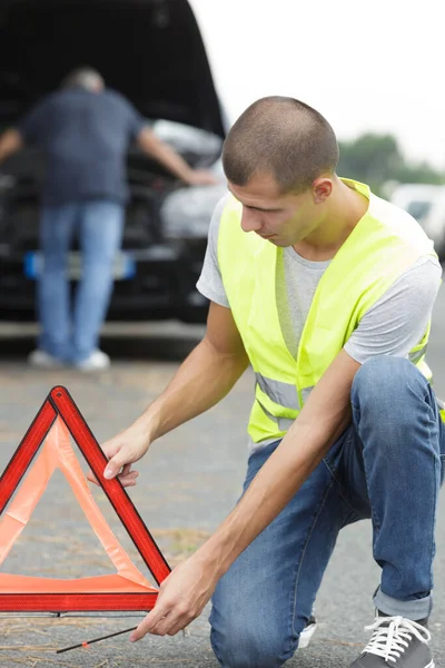 Giovane Uomo Mettendo Triangolo Avvertimento Dietro Sua Auto Guasto — Foto Stock