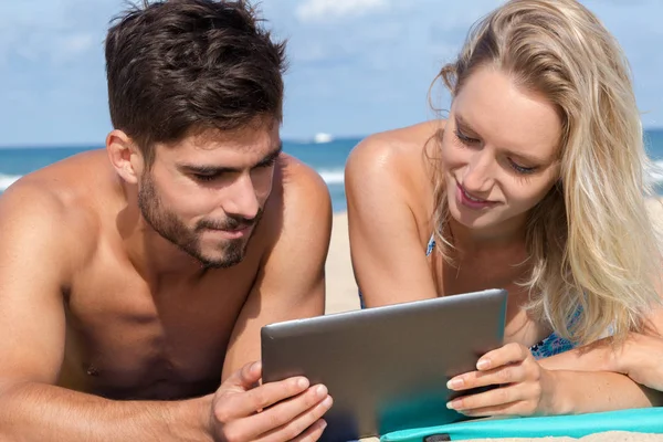 ビーチでタブレットを使うカップルは — ストック写真