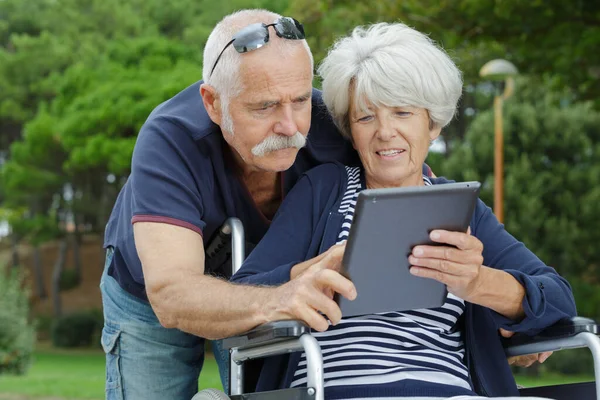 Pareja Ancianos Mirando Mujer Tableta Silla Ruedas — Foto de Stock