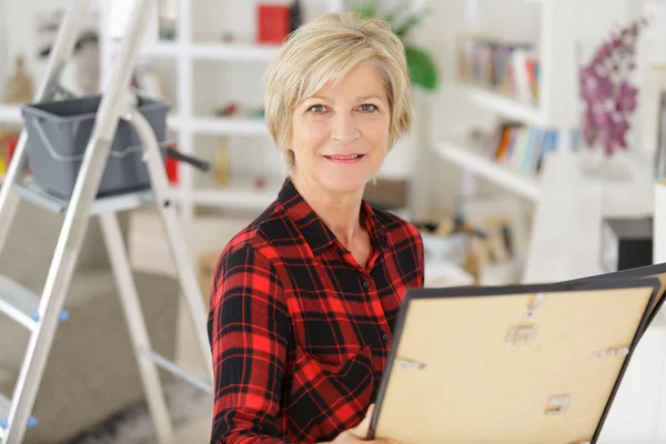 Ältere Frau Schaut Beim Umdekorieren Auf Pistenrahmen — Stockfoto