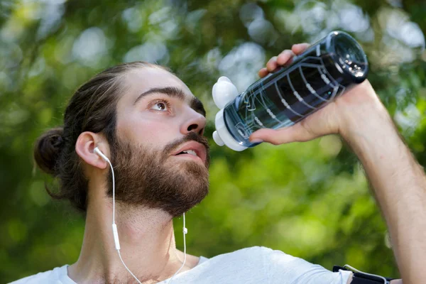 疲れた男が森の中で水を飲んで — ストック写真