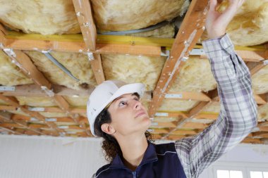 woman in builder hardhat and uniform installing suspended ceiling clipart