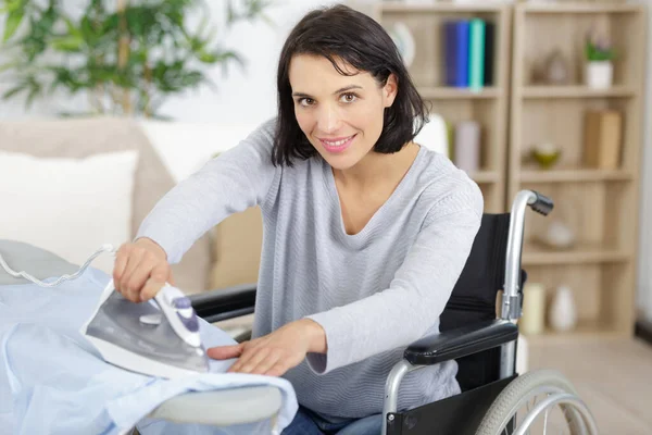 Donna Felice Sulla Sedia Rotelle Mettere Vestiti Nel Cestino — Foto Stock