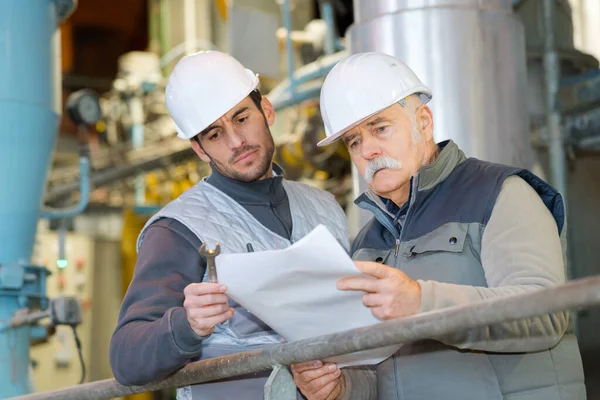 Deux Ingénieurs Masculins Matures Regardant Paperasserie Dans Usine — Photo