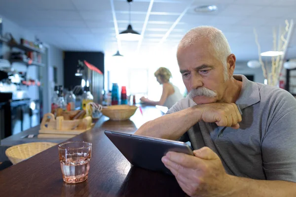 Starszy Mężczyzna Siedział Przy Barze Patrzył Tabliczkę — Zdjęcie stockowe