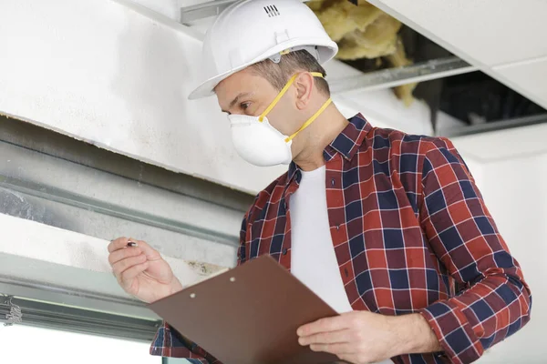 mature tradesman wearing mask up on a ladder