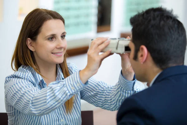 女视光师检查年轻男性病人的视力 — 图库照片