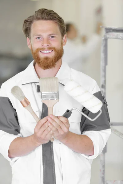 Joven Sonriente Guapo Hombre Sosteniendo Pinceles — Foto de Stock