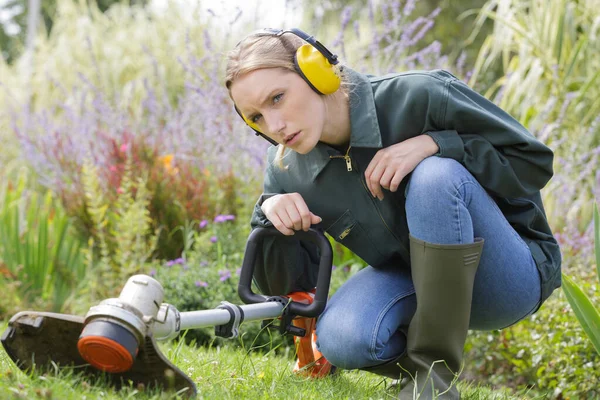 Young Female Gardener Crouching Examine Strimmer — Stock Photo, Image