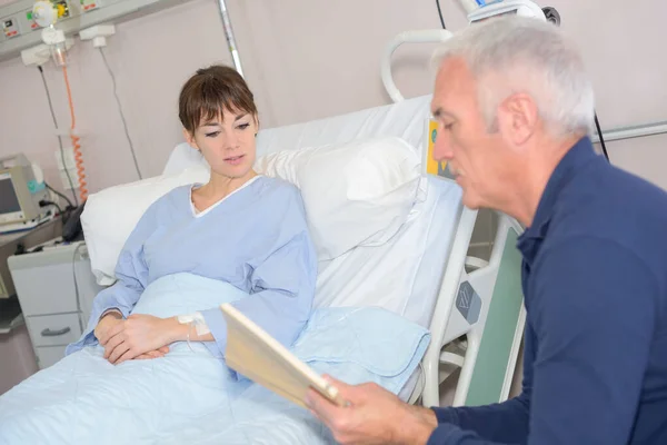 Woman Laying Hospital Bed While Dad Reading — Stock Photo, Image