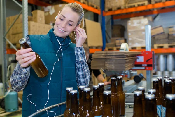Lavoratore Mettendo Suo Auricolare Mentre Guardando Una Bottiglia — Foto Stock