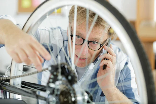 電話で自転車を修理する男は — ストック写真