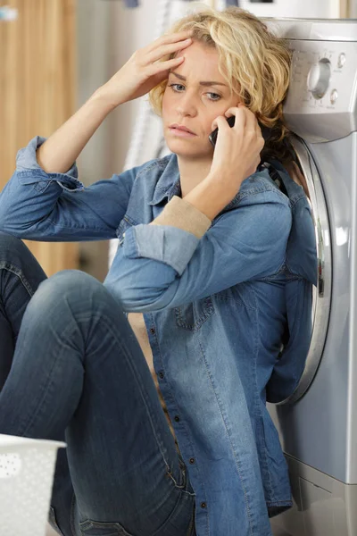 unhappy woman showing signs of fatigue near washing machine