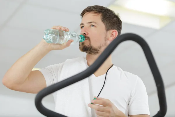 在健身房的跑步机上喝水的人 — 图库照片