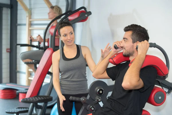 Entrenador Femenino Amigable Joven Que Ayuda Hombre Usando Máquina Gimnasio —  Fotos de Stock