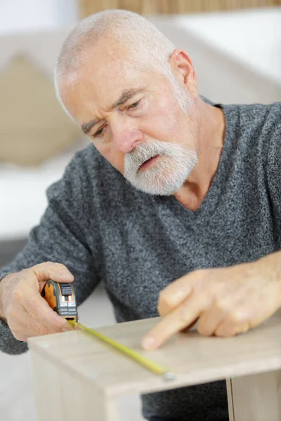 Senior Man Markeert Een Meting Een Houten Plank — Stockfoto