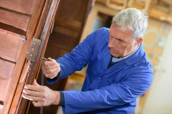 Starší Muž Opravuje Dveře Šroubovákem — Stock fotografie