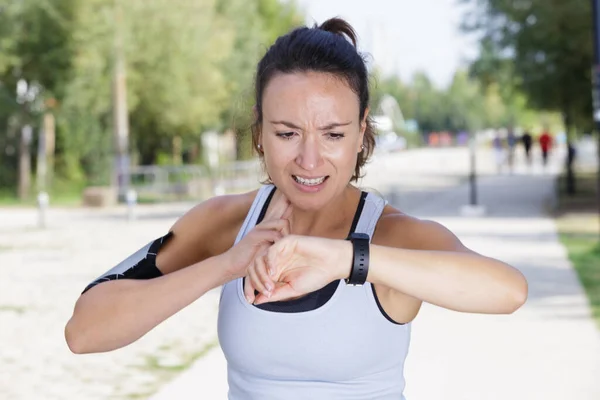 Trött Kvinnlig Löpare Tar Puls Och Tittar Smartwatch — Stockfoto